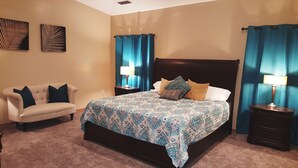 A bedroom with a bed, a chair, two nightstands, and a wall with two artworks. - Rustic home, spacious, clean, great for boaters, families, fishermen, business (Page)