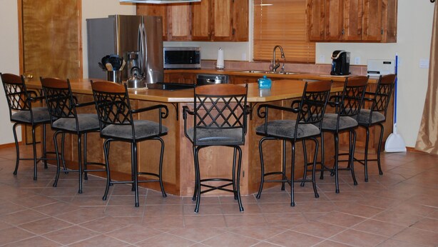 A kitchen with a central island, bar stools, wooden cabinets, and modern appliances. - Rustic home, spacious, clean, great for boaters, families, fishermen, business (Page)