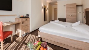 A hotel room with a bed, a desk, a chair, and a fruit bowl. - Hotel An Der Linah (Buxtehude)