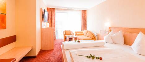 A hotel room with two beds, a sofa, a TV, and a window with curtains.