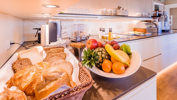 A breakfast buffet with bread, fruits, and beverages. - Hotel An Der Linah (Buxtehude)