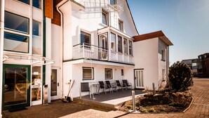 A two-story building with a balcony, outdoor seating area, and a small garden. - Hotel An Der Linah (Buxtehude)