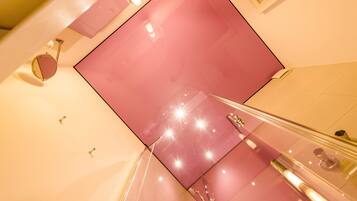 Un intérieur moderne avec un mur d’accent rose, une rambarde en verre et un sol réfléchissant.