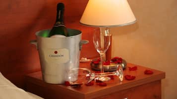 Ein Nachttisch mit einer Champagnerflasche, einem Weinglas und Rosenblüten.