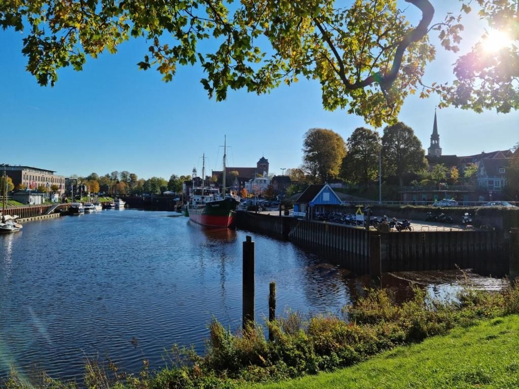 Une rivière avec des bateaux, un quai et des bâtiments en arrière-plan.