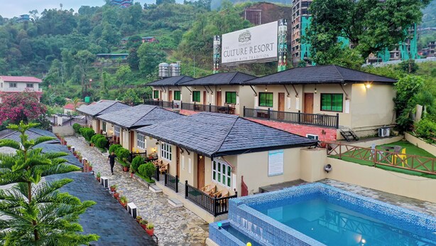 A resort with multiple buildings, a swimming pool, and lush greenery in the background. - The Culture Resort (Pokhara)