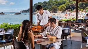 A seaside restaurant with outdoor seating overlooking the beach and sea. - Albamar Apartaments (Lloret de Mar)