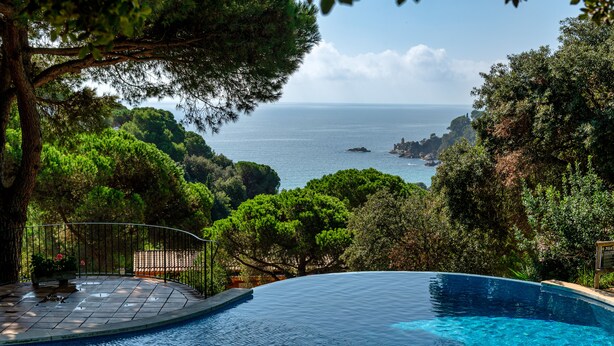 A infinity pool with a view of the sea and surrounding greenery. - Albamar Apartaments (Lloret de Mar)