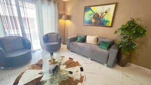 Una sala de estar moderna con una mesa de centro de vidrio, dos sofás, una lámpara de pie y un cuadro en la pared.