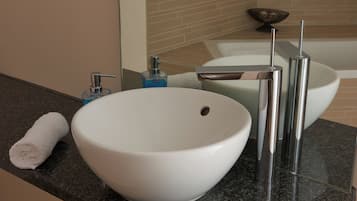 A modern bathroom with a white sink, chrome faucet, and a towel on the counter.