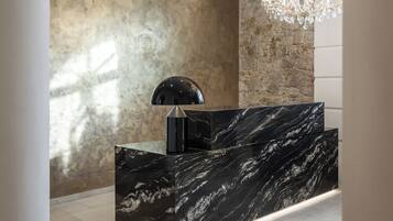 A reception area with a marble counter, a chandelier, and a stone wall.