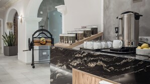 Une cuisine moderne dotée d’un plan de travail en marbre, d’un coin café et d’un banc en bois sur lequel sont posées des assiettes.