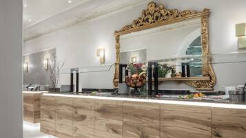 A modern bathroom with a large mirror, wooden cabinetry, and a tiled floor.