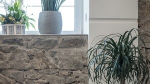 Un salon moderne avec un canapé en cuir noir, un mur en pierre et une plante en pot.