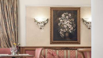 A dining area with a round table, chairs, a sofa, and a wall-mounted painting.