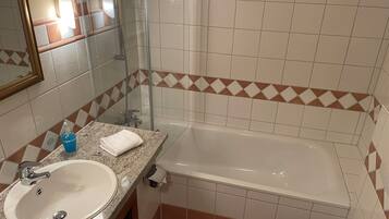 Un baño con lavamanos, espejo, ducha e inodoro.