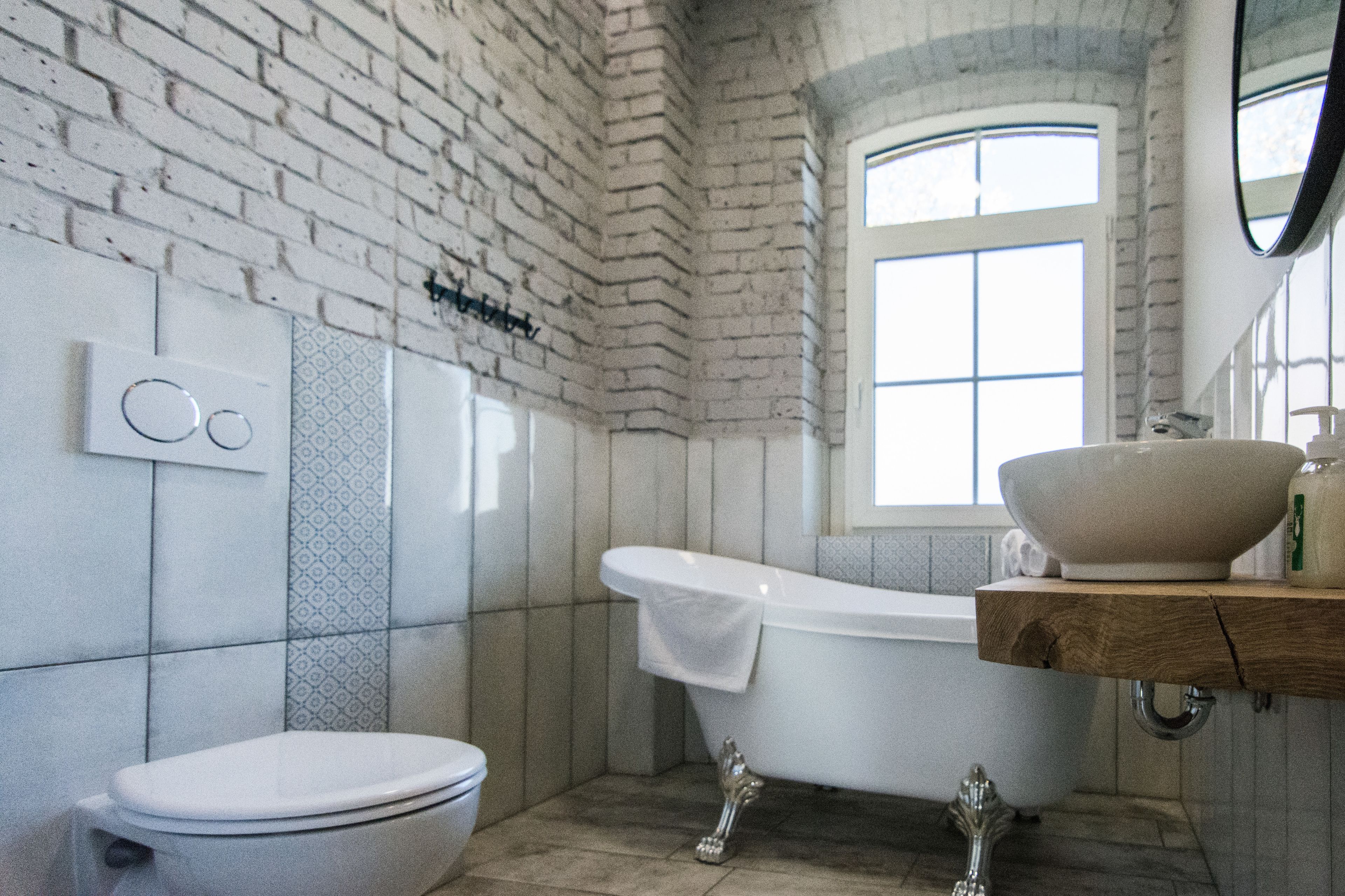 A bathroom with a white bathtub, a white toilet, and a wooden vanity with a large bowl sink.