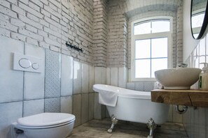 Une salle de bain avec une baignoire blanche, des toilettes blanches et un meuble-lavabo en bois doté d’un grand lavabo en cuve.