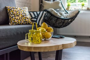 Une table ronde en bois, sur laquelle se trouvent un bocal en verre, des citrons et une télécommande.