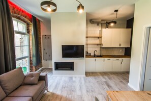 Un salon moderne avec un canapé, un téléviseur à écran plat et une cheminée.