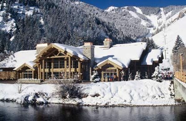 A lodge with a large wooden structure, a snow-covered roof, and a view of a lake and mountains. - SV155 - Walk to Lifts & Town - Hot Tub & Pool (Ketchum)