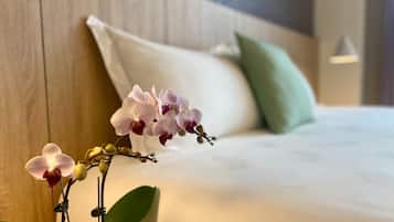 A neatly made bed with white linens, a green pillow, and a wooden headboard.