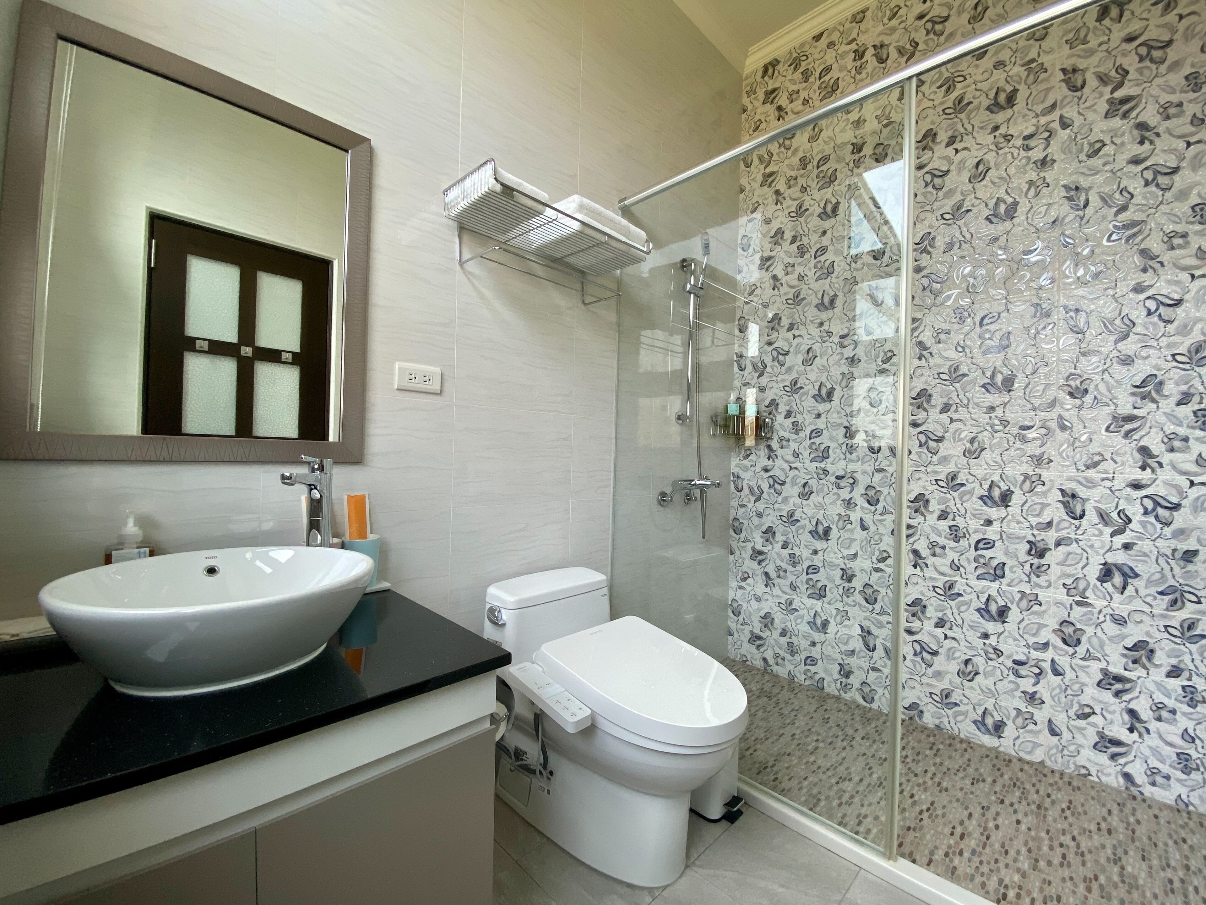 A bathroom with a large sink, toilet, and a glass-enclosed shower area.