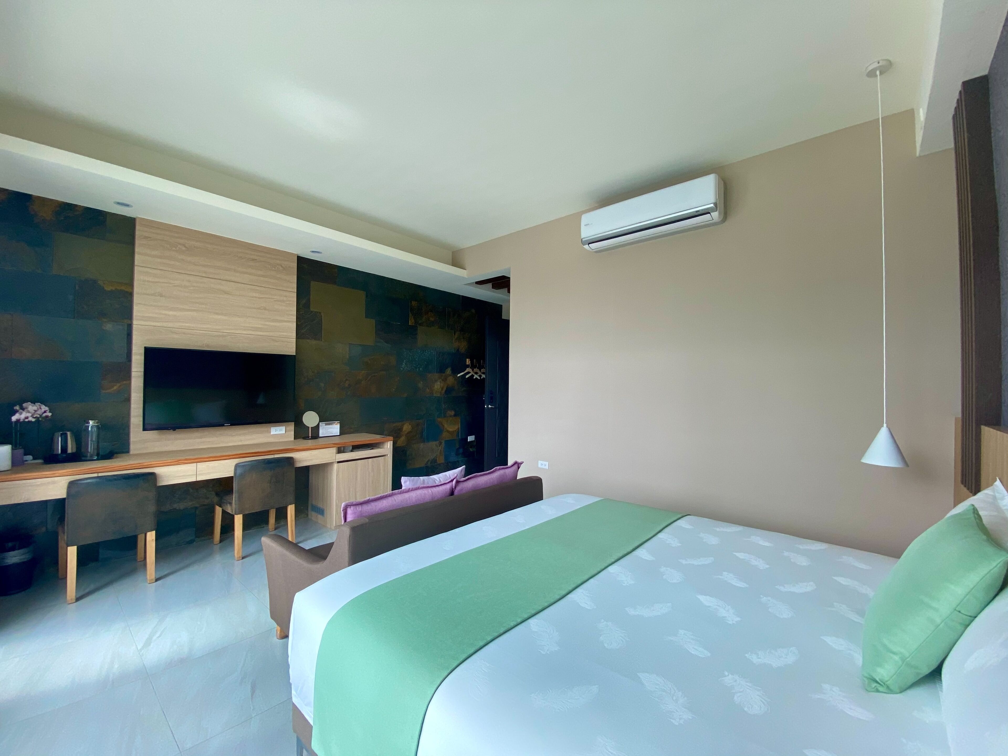 Habitació d'hotel moderna amb un llit, una taula de treball i una zona d'estar.
