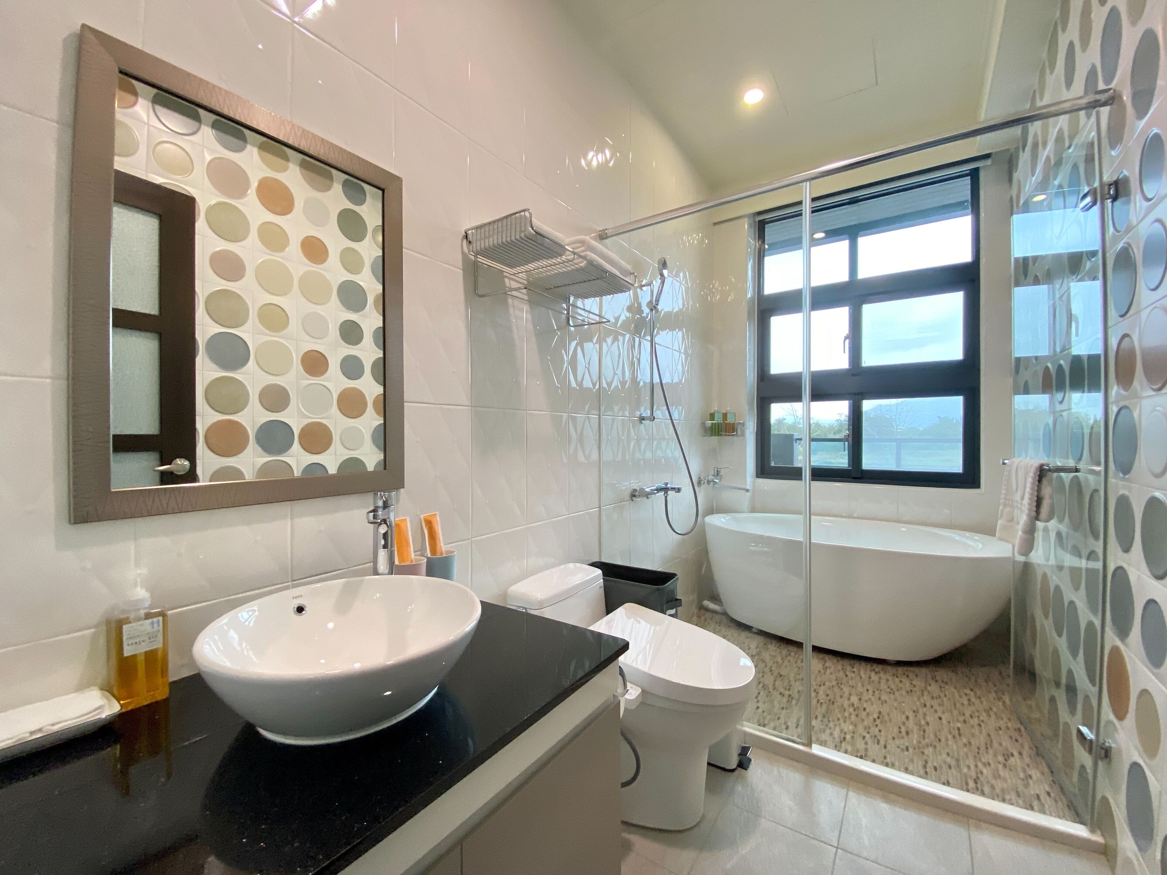Un baño moderno con un lavamanos ovalado grande, un inodoro y una bañera independiente.