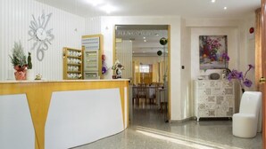 A hotel reception area with a reception desk, a clock, a decorative wall piece, a cabinet with patterned drawers, and a painting on the wall. - Hotel San Marco (Rionero in Vulture)