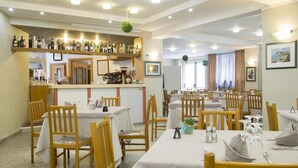 A restaurant with multiple tables and chairs, a bar area with various bottles, and a counter. - Hotel San Marco (Rionero in Vulture)