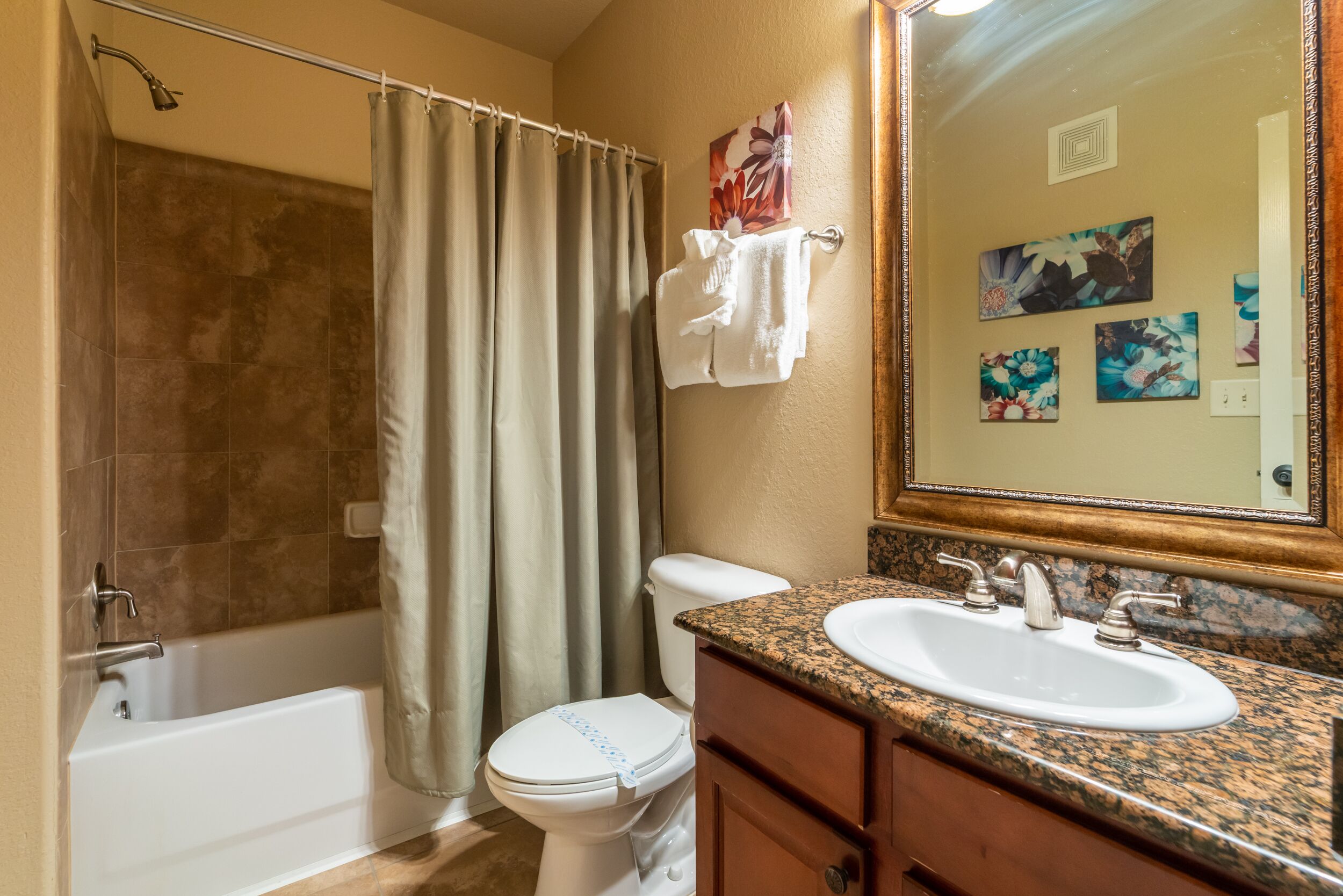 A bathroom with a bathtub, toilet, sink, and a mirror.