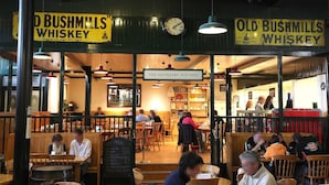 A restaurant interior with wooden furniture, hanging lights, and a clock. - Carnately Lodge Ballycastle (Ballycastle)