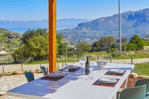A table set for two with a view of a coastal town and mountains in the background.