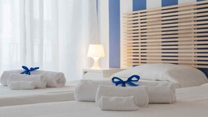 A hotel room with neatly folded towels with blue ribbons, a bedside lamp, and a striped headboard. - B&b Zammù (Palermo)
