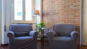 A room with two grey armchairs, a small table with a lamp, and a potted plant. - B&b Zammù (Palermo)