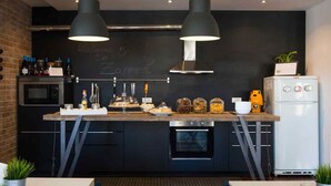 A modern kitchen with a central island, black cabinets, stainless steel appliances, and a chalkboard wall. - B&b Zammù (Palermo)