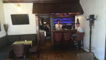 A restaurant with a bar area, wooden furniture, and tiled flooring.