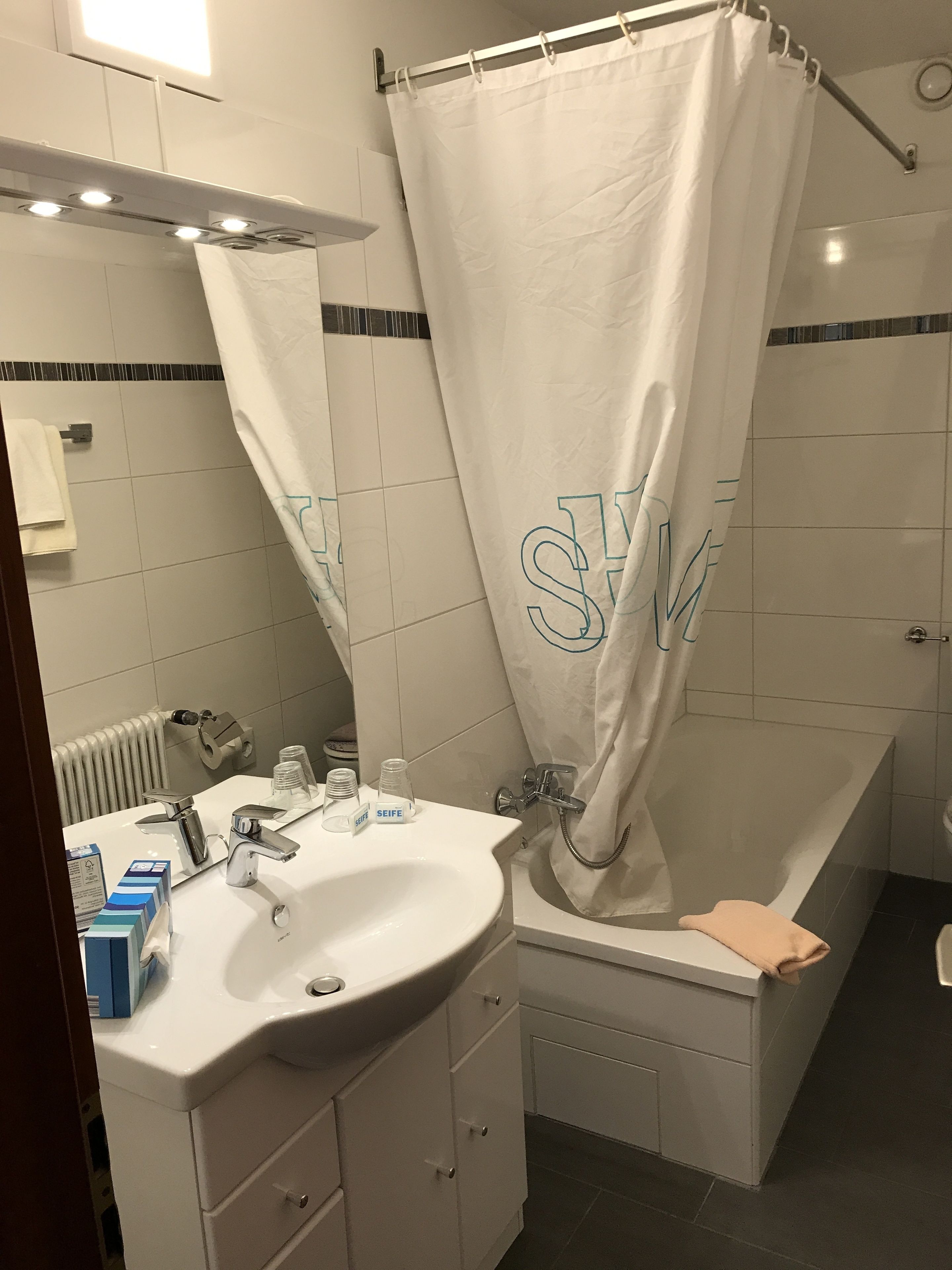 Un baño con lavamanos blanco, espejo y bañera.