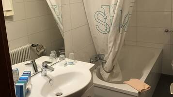 Un baño con lavamanos blanco, espejo y bañera.