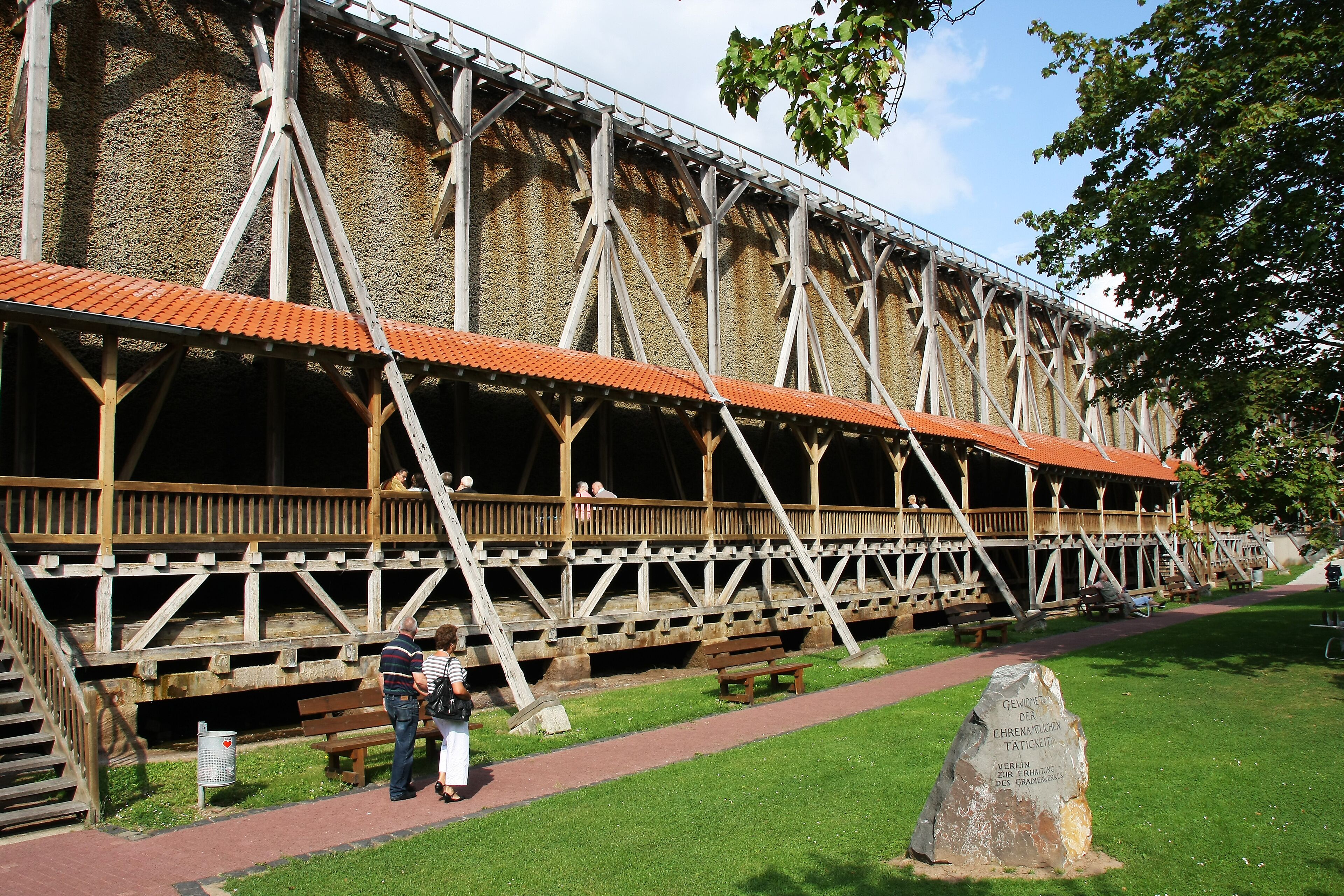 A large wooden structure with a red roof, possibly a historical building or museum.