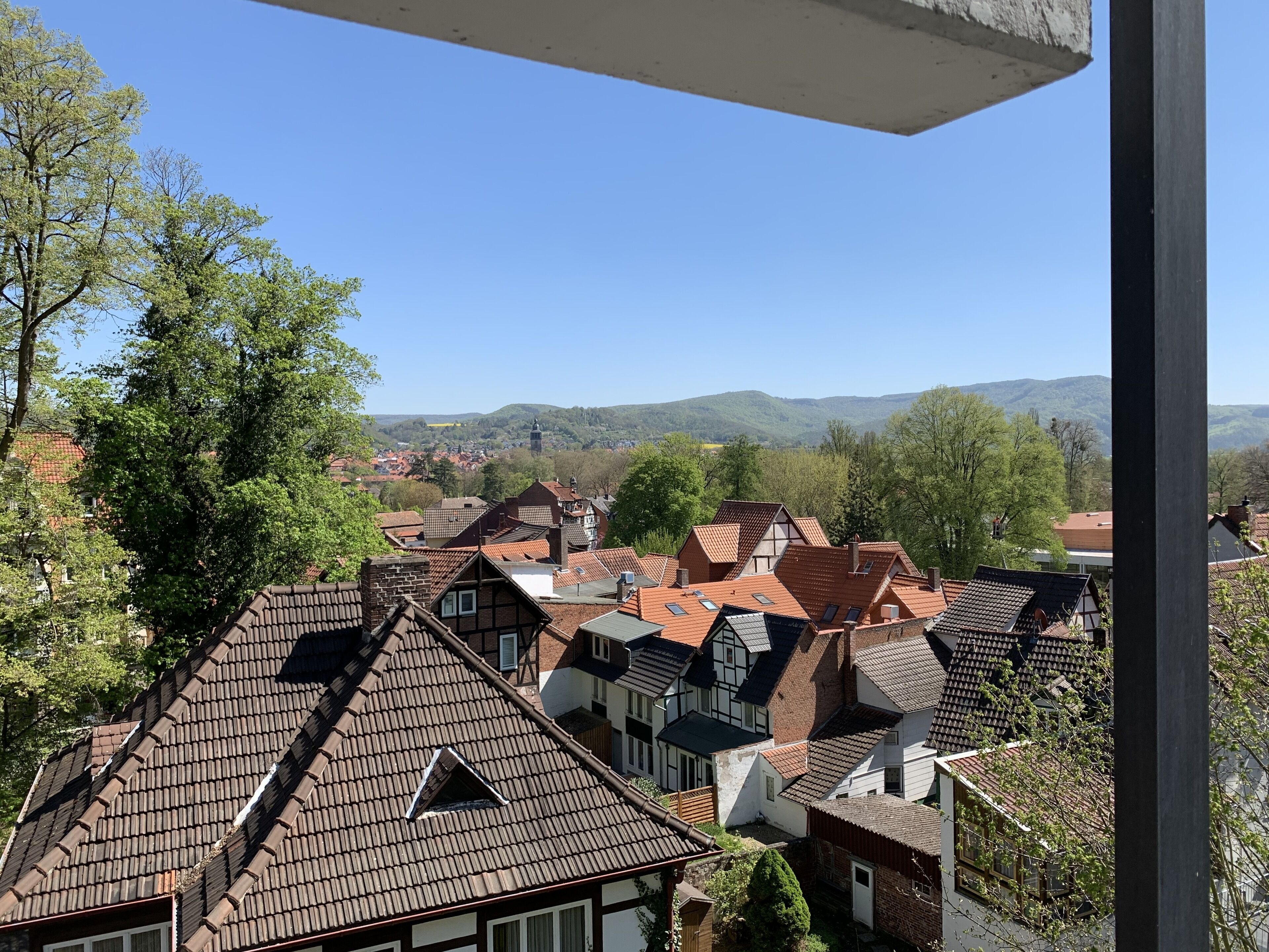Vista di case europee tradizionali con tetti spioventi e una chiara visuale del paesaggio circostante, tra cui colline e alberi.
