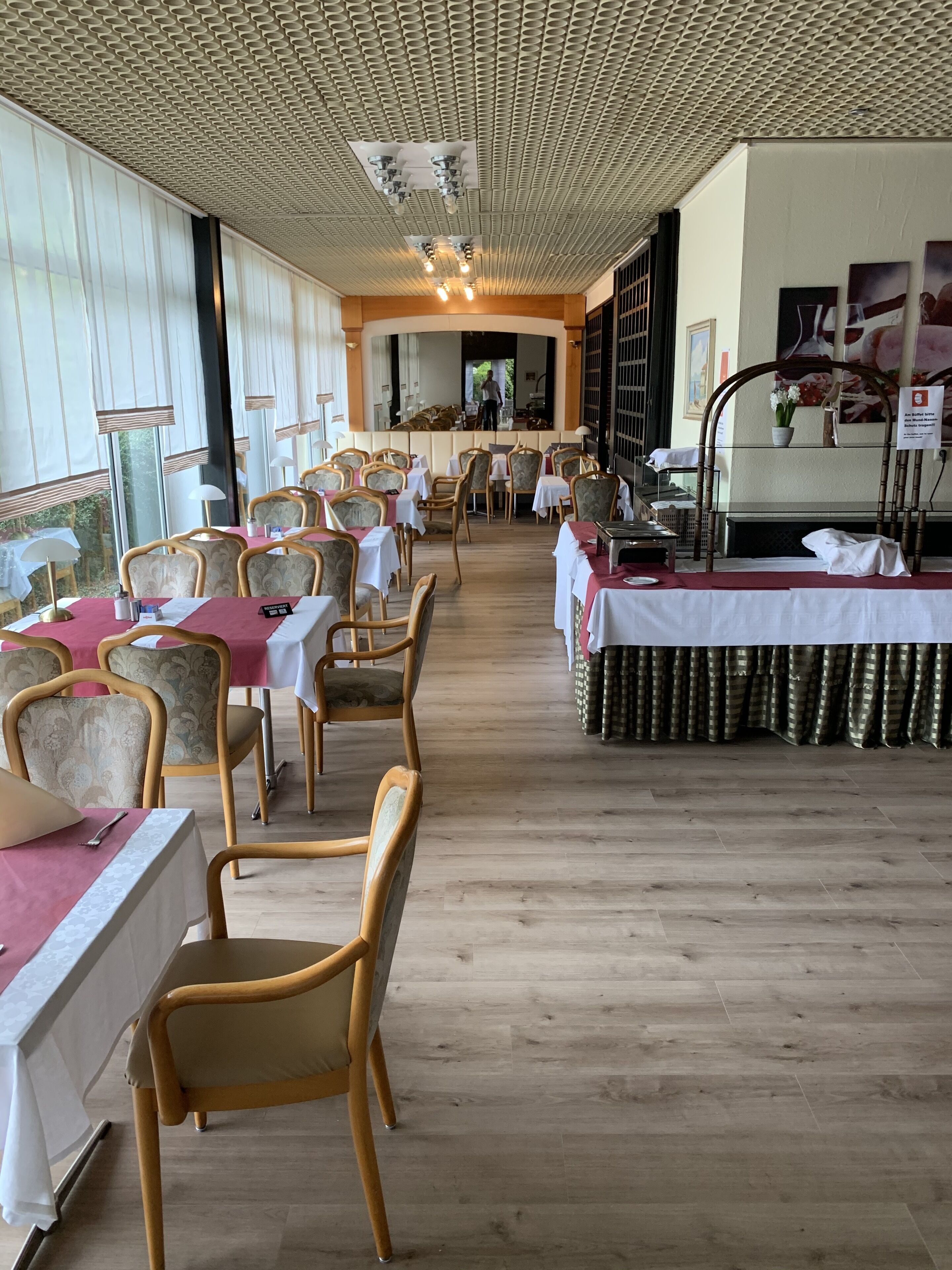 Un restaurante con suelo de madera, mesas con manteles blancos y sillas de mimbre.