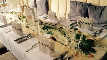 A table set for a formal event with white tablecloths, silverware, and glassware.