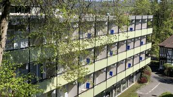 A multi-story building with balconies, surrounded by greenery.