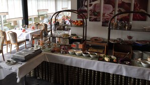 Ein reichhaltiges Buffet mit verschiedenen Speisen und ein Essbereich mit Stühlen und Tischen.