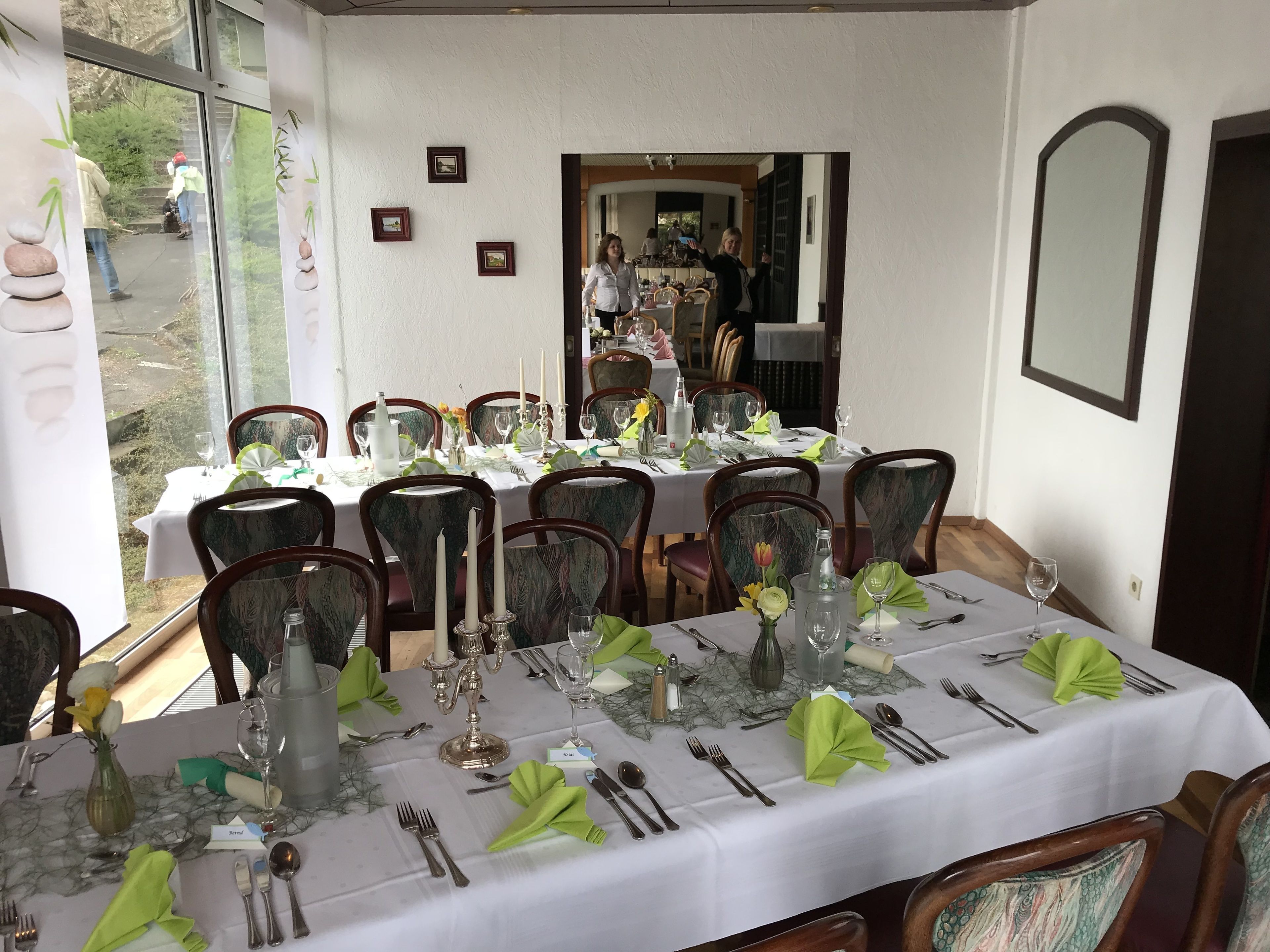 A dining area with tables set for a meal, chairs, and a view of the outdoors.