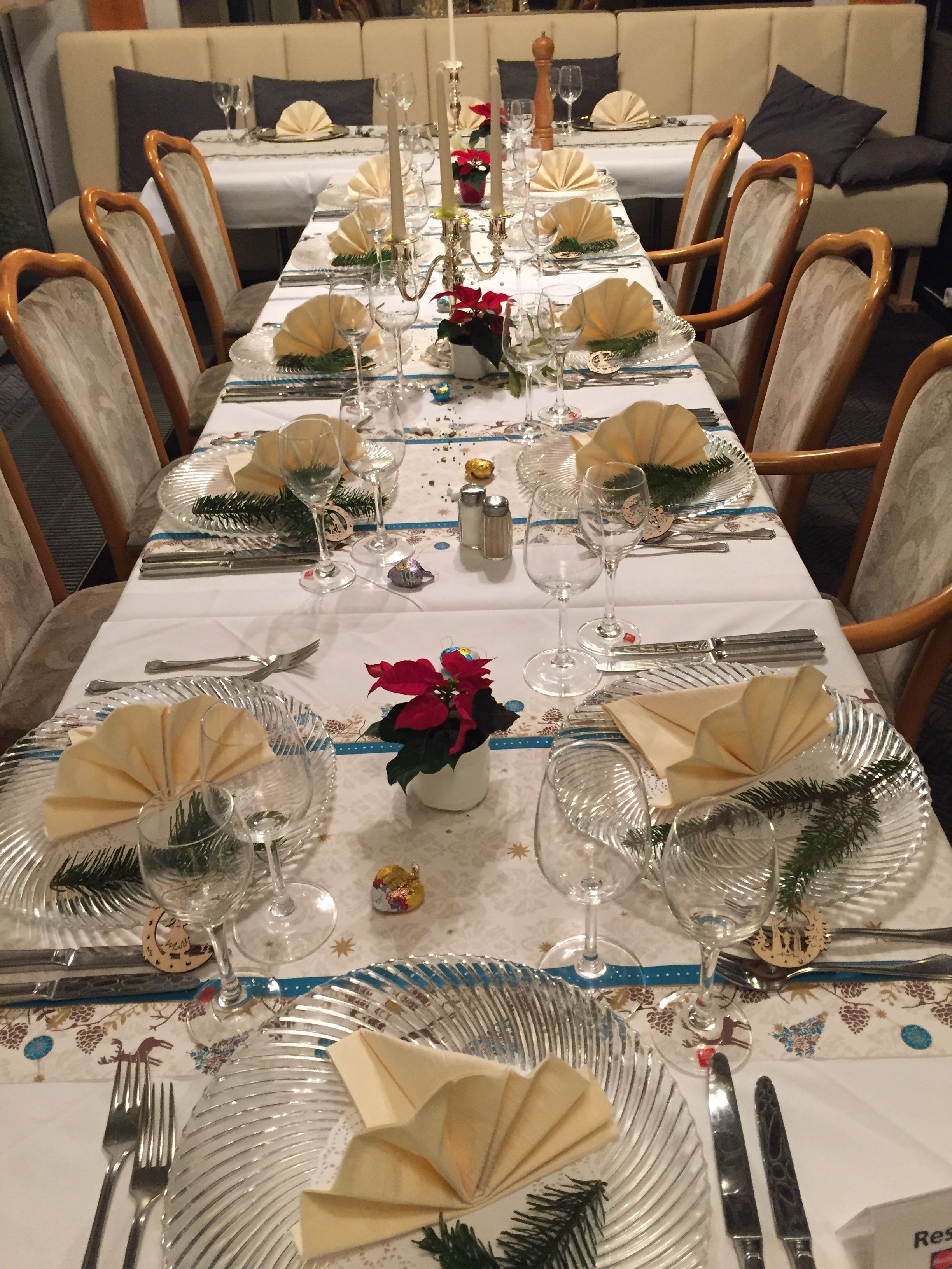 A long dining table set with multiple place settings, including plates, cutlery, and glassware.