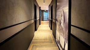 A hallway with a herringbone patterned floor, dark walls, and a large wall-mounted artwork of palm trees. - Aerotel Cebu (Lapu-Lapu)