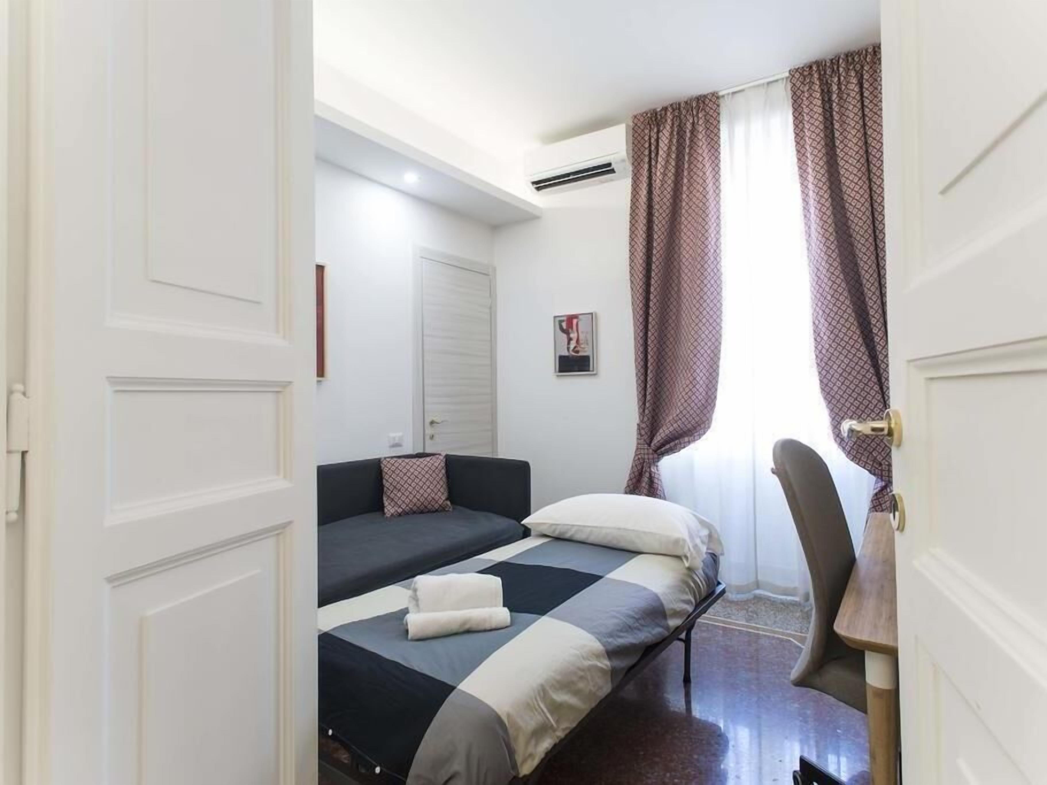 A bedroom with two beds, a desk, and a chair.